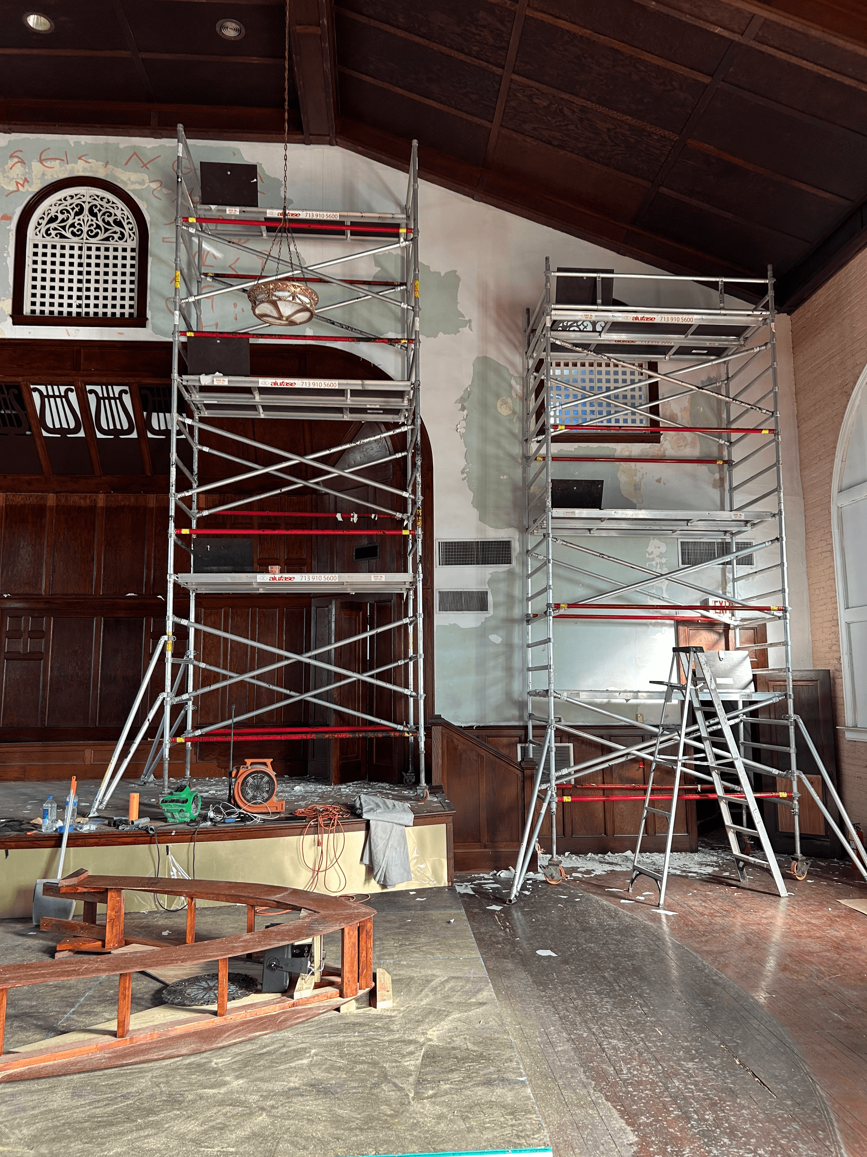 Tall metal scaffolding stands against peeling walls in a room with dark wood paneling.